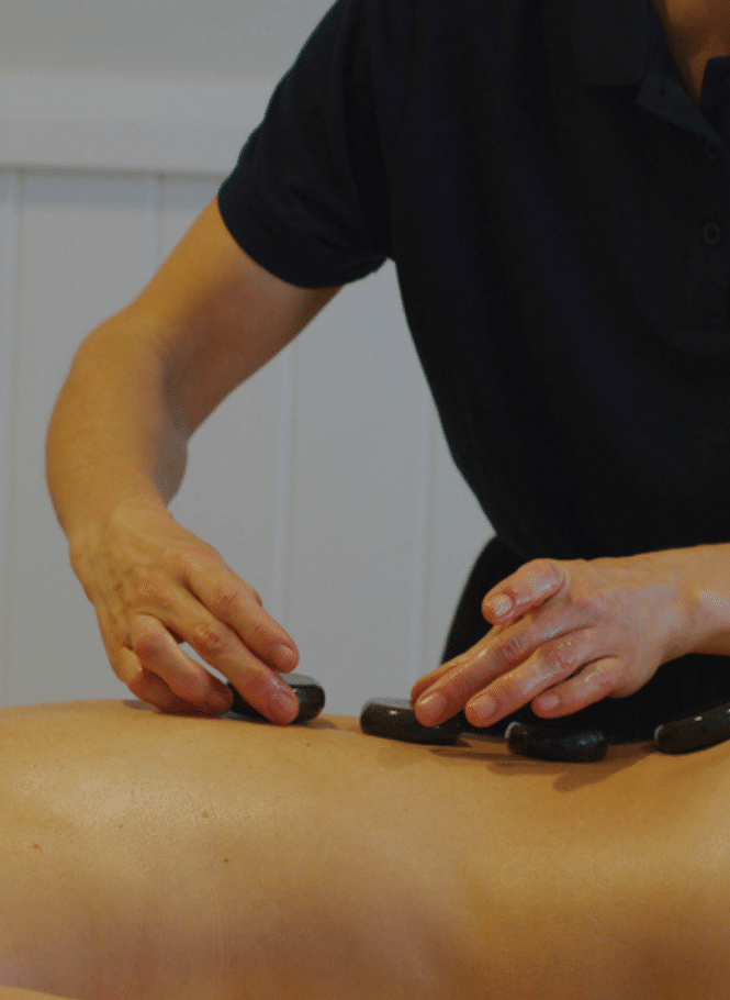 Massage therapist putting hot stones on guest's back
